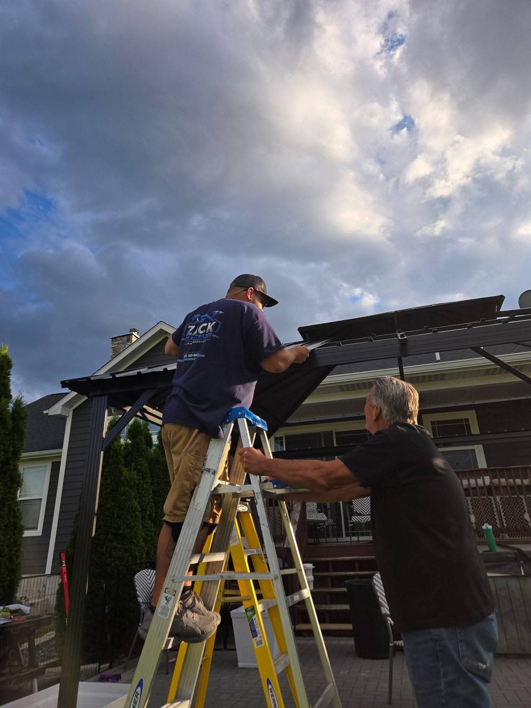 Zack of All Trades owner assembling a gazebo roof from a ladder